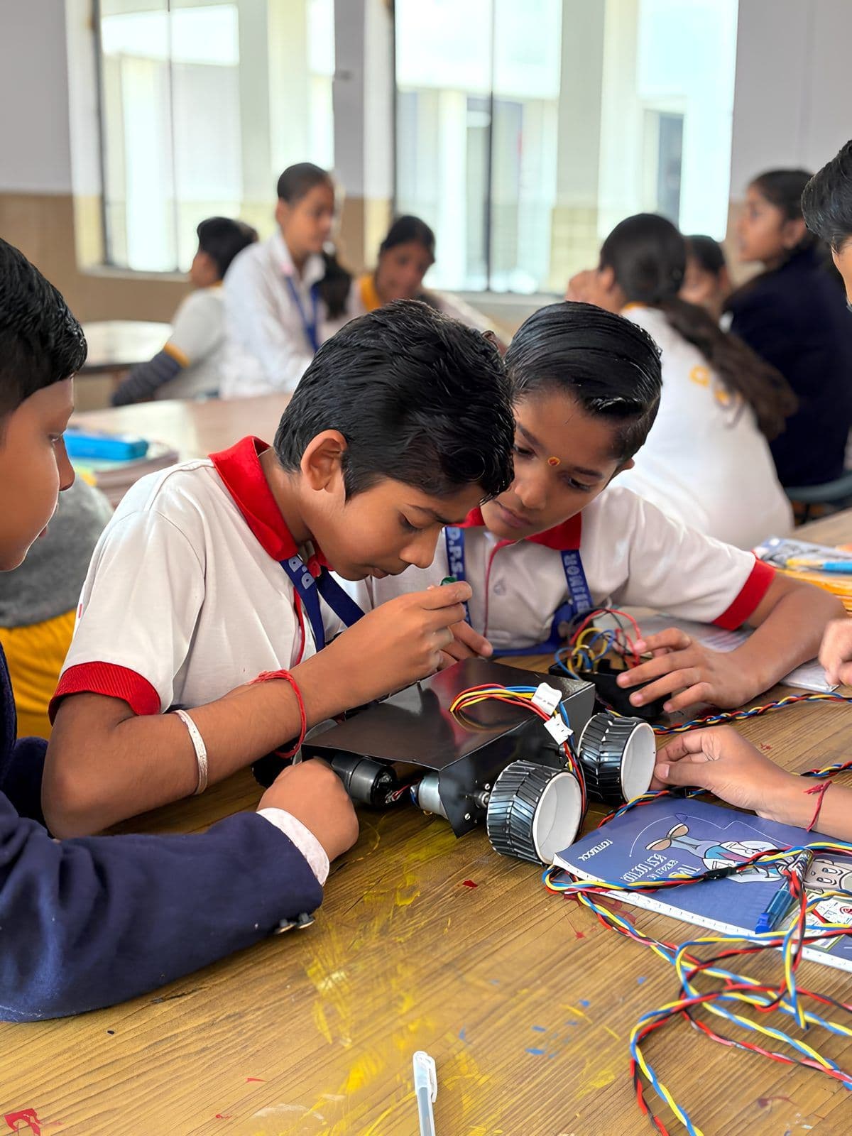 Students assembling a robot car kit in a classroom